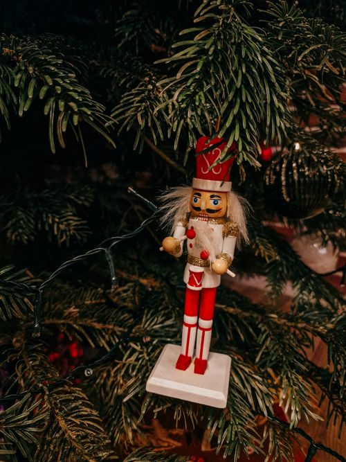 Free Charming nutcracker doll hanging on a Christmas tree branch, creating a festive holiday ambiance. Stock Photo