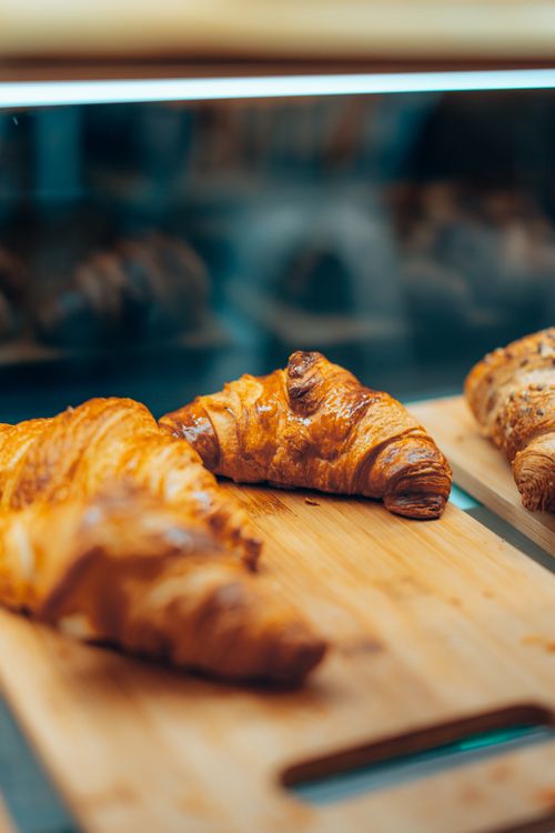 Free Golden brown croissants displayed on a cutting board, perfect for breakfast or dessert ideas. Stock Photo