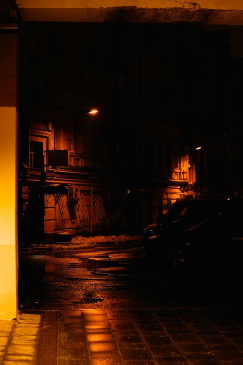Free Dramatic street scene in a dimly lit Moscow alleyway, showcasing wet cobblestones and atmospheric lighting. Stock Photo