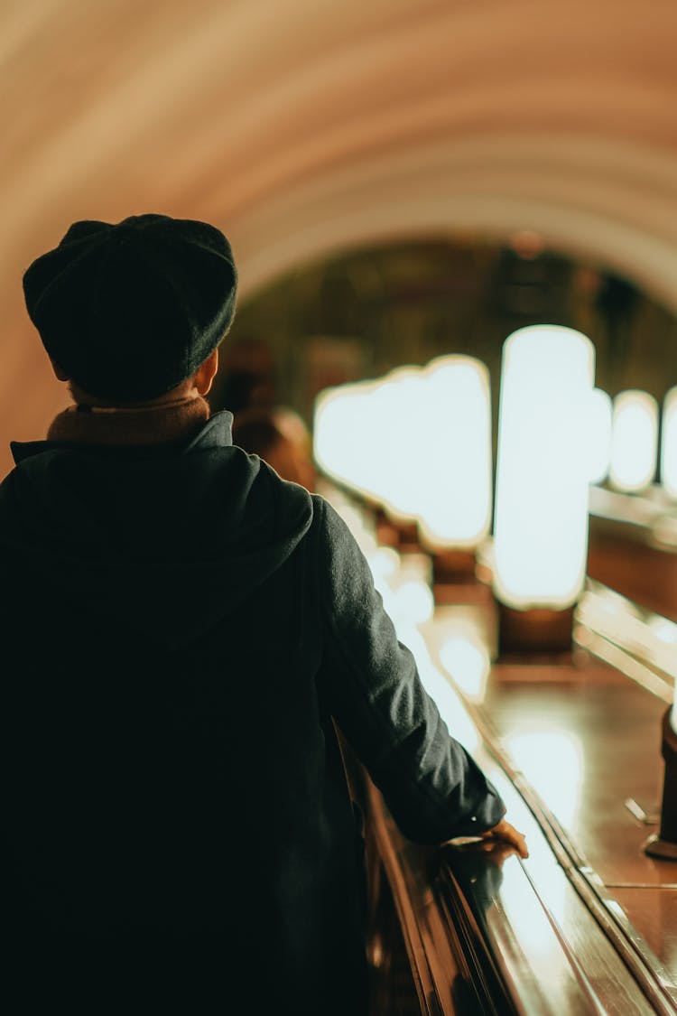 Back Of A Man In A Beret Walking Along A Railing