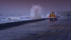 戏剧性的沿海场景，暴风雨天气里海浪撞击海堤和车辆