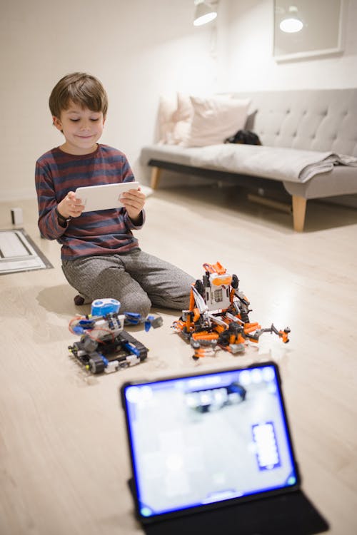 Boy Playing in Living Room with Robots and Tablet