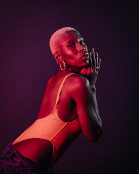 Bold portrait of a fashionable woman with dyed short hair under dramatic red lighting.