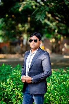 Portrait of a confident man in a blazer and sunglasses standing outdoors.