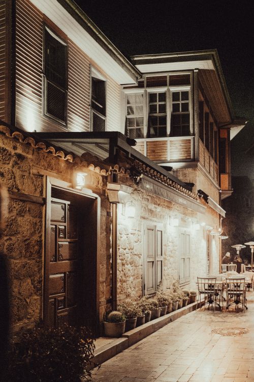 Free An illuminated restaurant patio with rustic architecture captured at night, showcasing inviting ambiance. Stock Photo