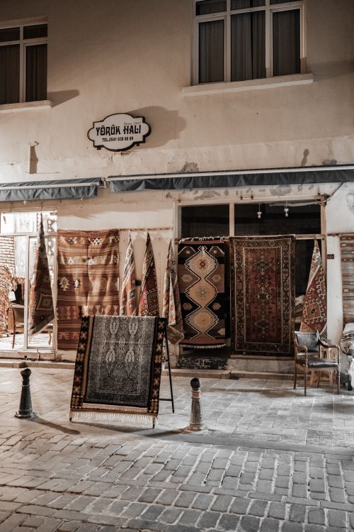 Free A traditional shop with a display of Persian carpets and rugs during nighttime. Stock Photo