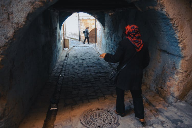 Woman Walking In Tunnel In Town