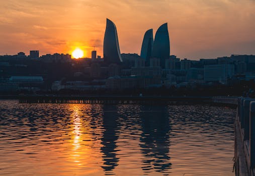 Silhouette of Baku's Flame Towers against a stunning sunset backdrop reflecting in the Caspian Sea.