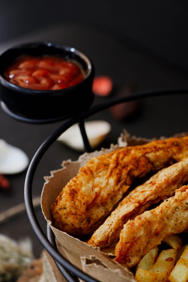 Delicioso peito de frango frito crocante servido com ketchup, perfeito para uma refeição saborosa.