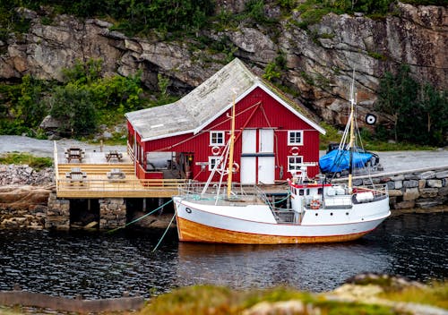 Free Boat near Wooden Traditional House in Mountain Foot Stock Photo