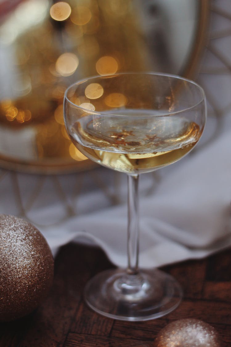 Close-up Of A Glass Of White Wine And Glitter Christmas Baubles 