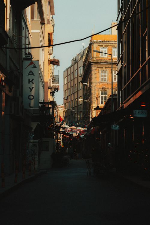 Free Sunlit narrow street lined with shops and historical buildings in an urban district. Stock Photo