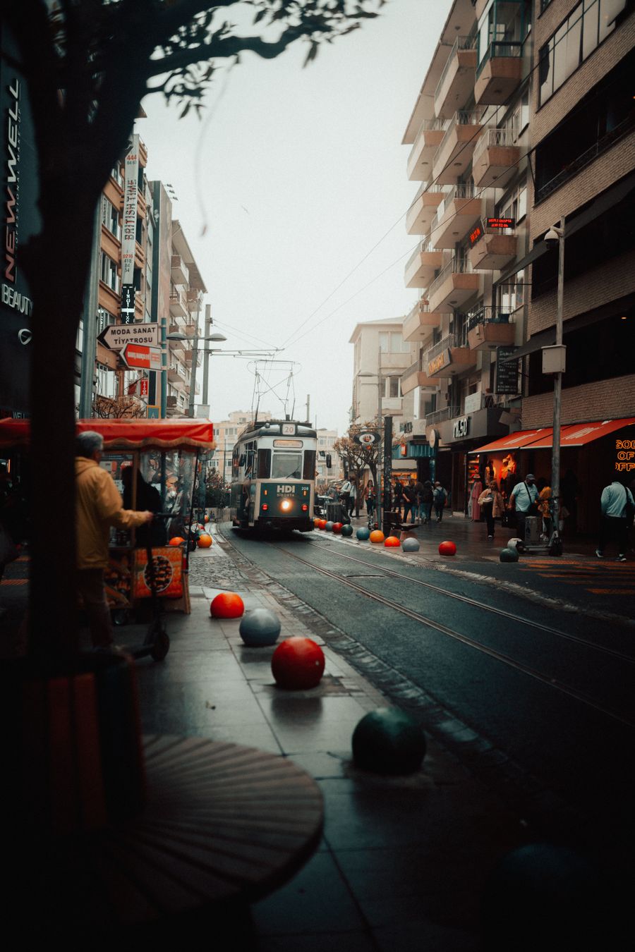 Yağmurlu bir şehir sokağında tramvay ve yayalar