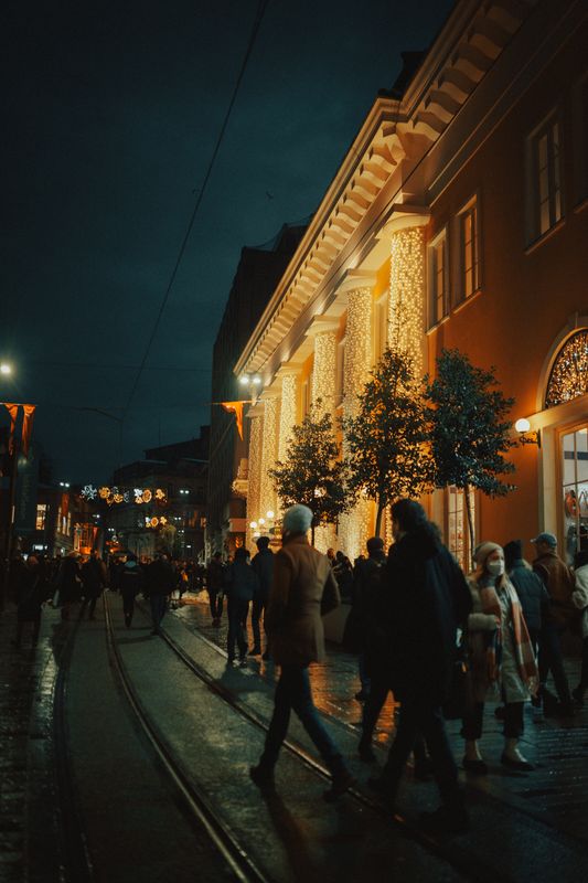 Gece bayram ışıklarıyla süslü, yürüyen kalabalıkla dolu bir sokak