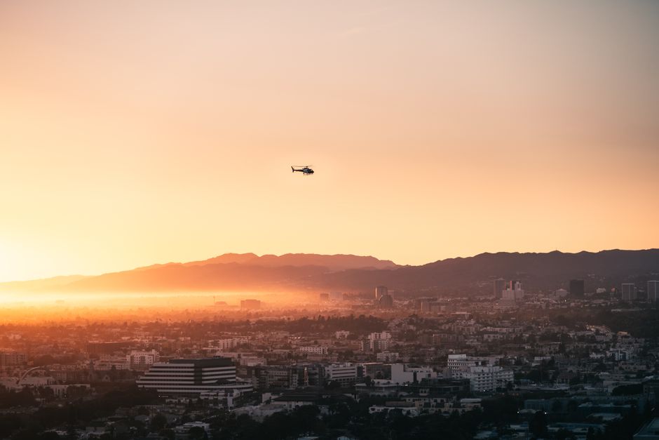 Stunning Los Angeles Live Private Helicopter Tour Review: Soaring Above LA's Most Iconic Landmarks Review 2026 - A breathtaking aerial view of Los Angeles with a helicopter flying at sunrise over the cityscape.