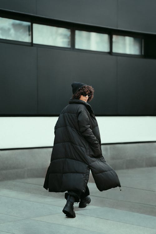 Woman in a Long Winter Coat Walking Down the Sidewalk and Looking over her Shoulder