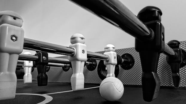 Close-up view of a foosball table in black and white highlighting player and ball.