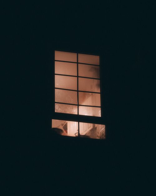 Free A solitary window softly illuminated from within, creating a mysterious urban night scene in London. Stock Photo