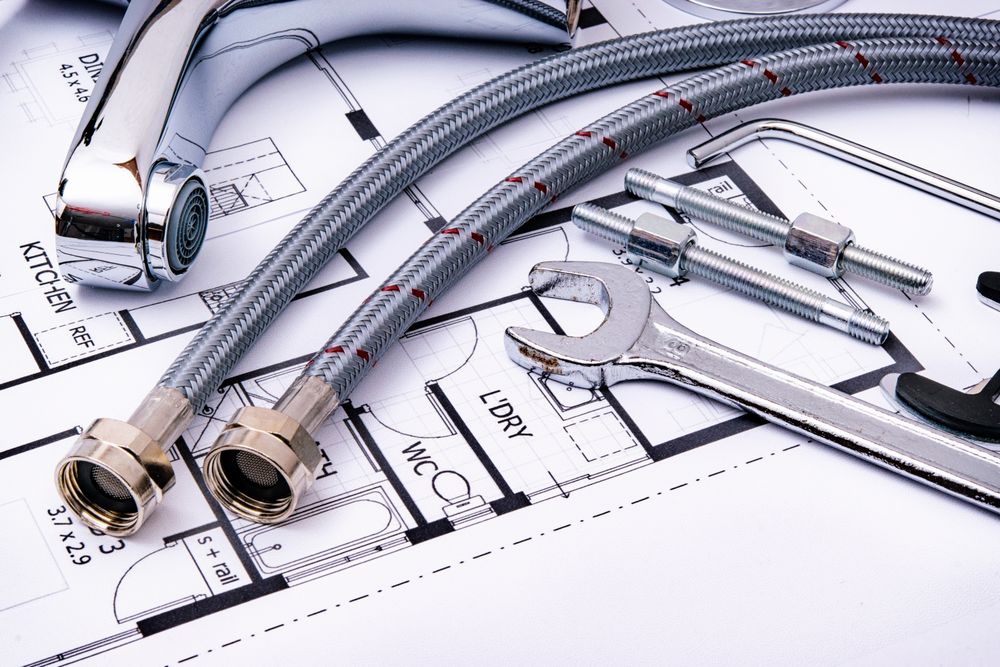 Plumbing tools and fittings laid out over a blueprint