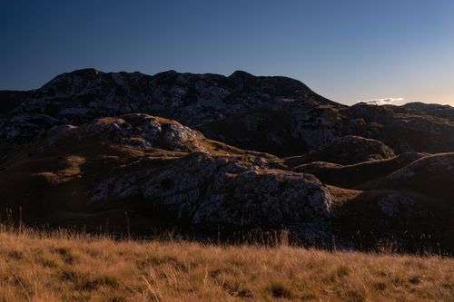 Free Serene rocky hill landscape with dry grass under a clear dusk sky. Stock Photo