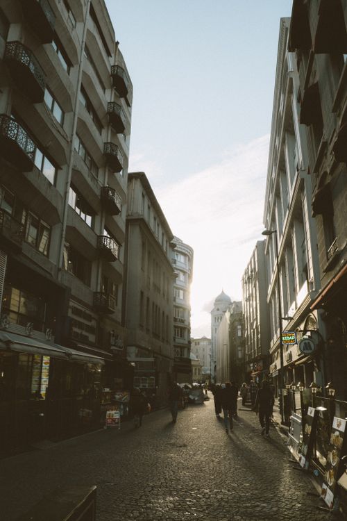 Free Narrow city street with sunlit cobblestones and urban architecture, capturing an active city vibe. Stock Photo