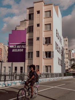 Cyclist riding in Campos Elíseos, Brazil, with colorful mural backdrop and urban ambiance.