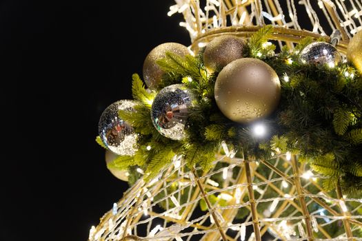 Brightly lit Christmas decorations with shiny ornaments and green garland.