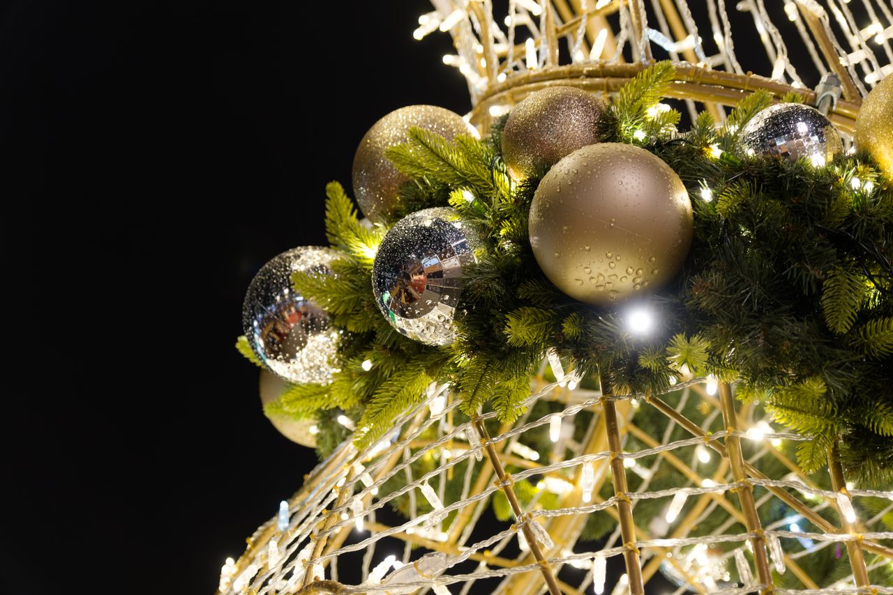 brightly lit christmas decorations with shiny ornaments and green garl