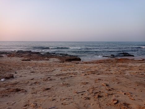 A serene sandy beach at sunset with gentle waves and a peaceful atmosphere.