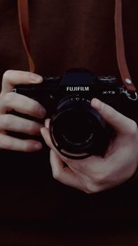 Hands holding a Fujifilm camera, showcasing technology and precision.