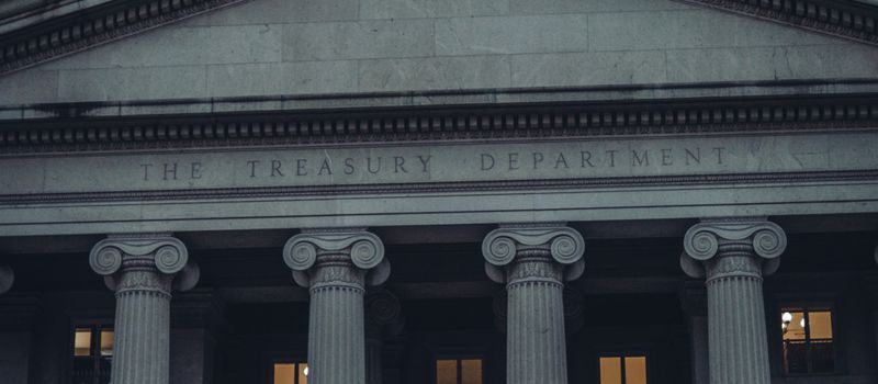 米財務省の建物と国旗が映る夕景。長期金利上昇というニュースに合わせ、米国の財政・金融政策を象徴する情景のイメージ。