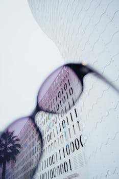 Abstract view of modern architecture with binary code pattern through stylish sunglasses.