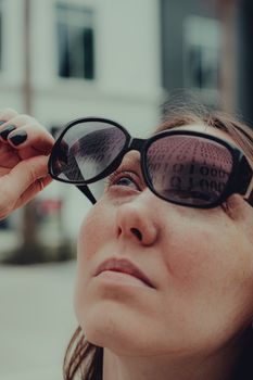 Close-up of a woman looking up with sunglasses reflecting numbers.