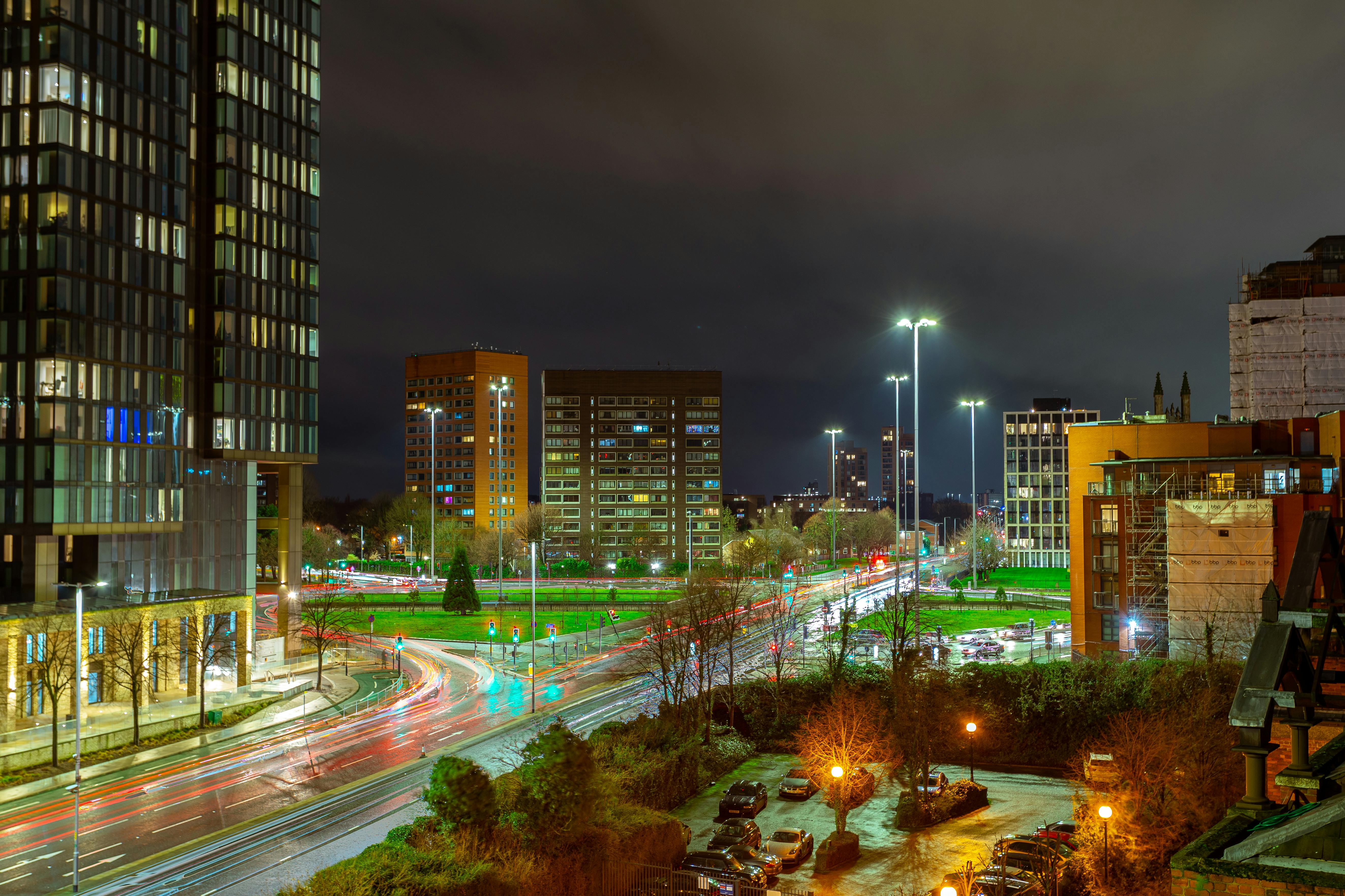 Cityscape of Manchester at night with buildings and illuminated streets, showcasing urban life.