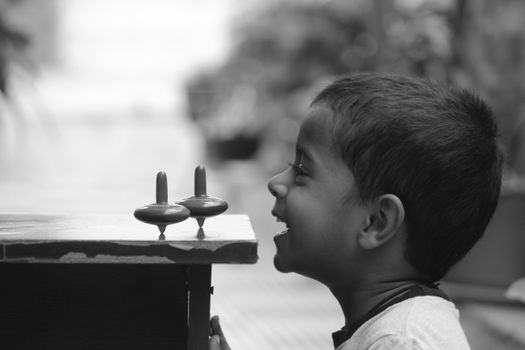 A child having fun with spinning tops, captured in a black and white portrait.