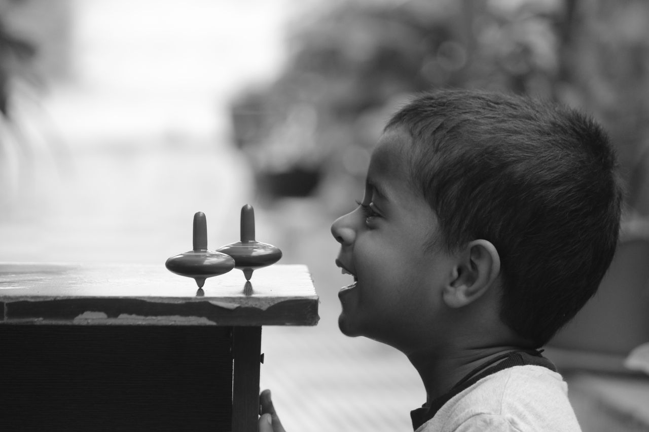 a child having fun with spinning tops captured in a black and white po