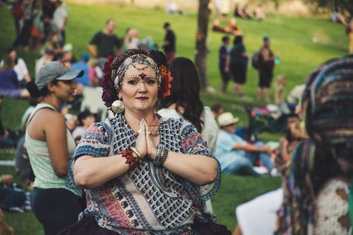 Free A woman dressed in traditional attire with face paint, at a lively outdoor festival in a park. Stock Photo
