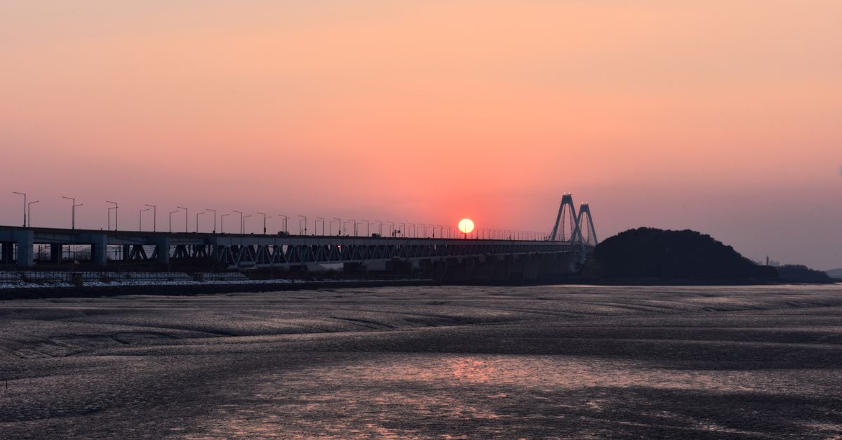 Captivating view of Yeongjong Bridge during sunset in Incheon, South Korea with serene waters and a warm orange sky. visual (Photo: joon young, Park / Pexels)