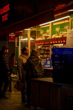People gather at an illuminated fast food stand at night, enjoying the urban atmosphere.