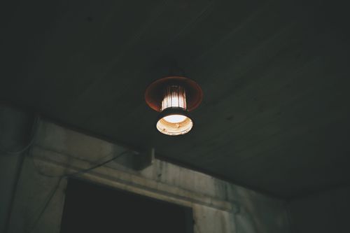 Free A moody vintage ceiling lamp casting warm light in a dark room with rustic vibes. Stock Photo