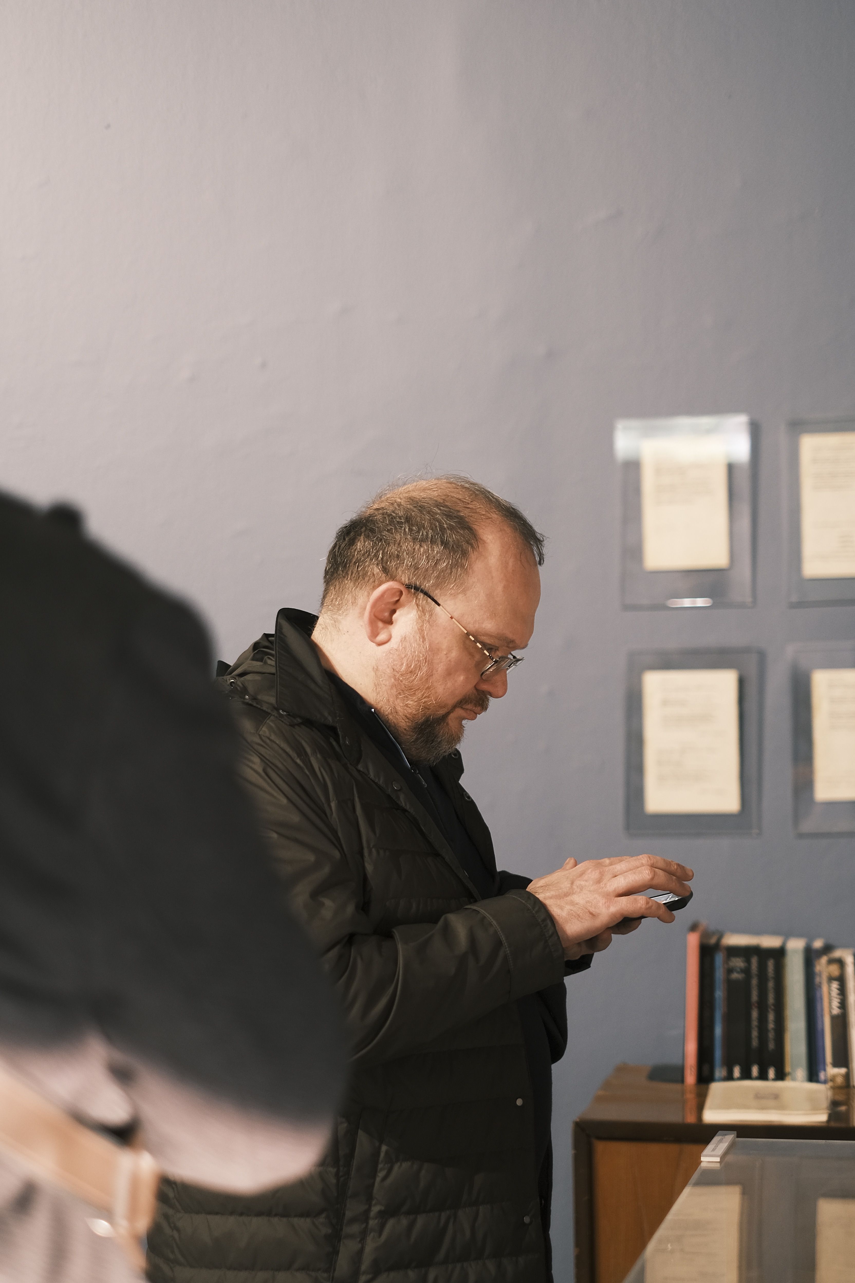Adult man using smartphone in a museum, engaging with exhibits.