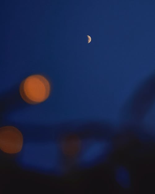 A moon is seen in the sky with some lights