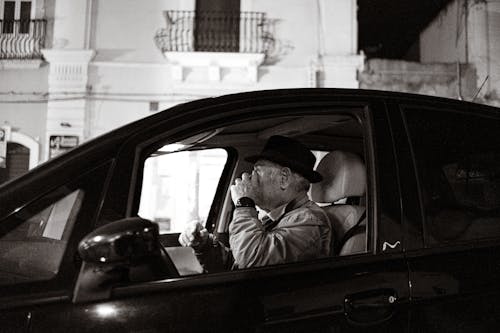 Grayscale Photo of a Man inside the Black Car