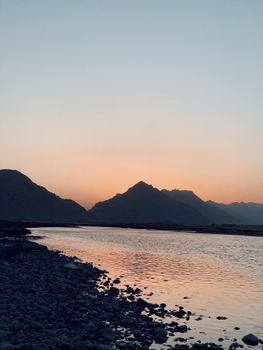 Peaceful sunset view in Qaladiza, Iraq, with mountain silhouette and reflective water.