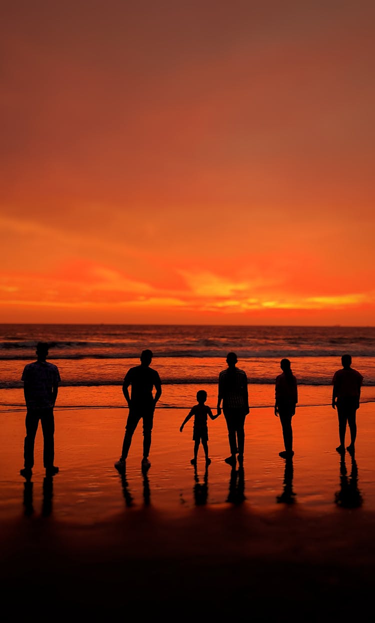 Silhouettes Of People Standing At A Beach