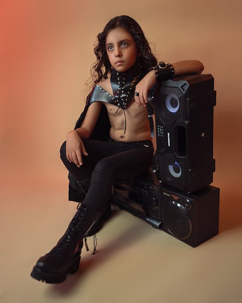 A Boy Sitting with Speakers 