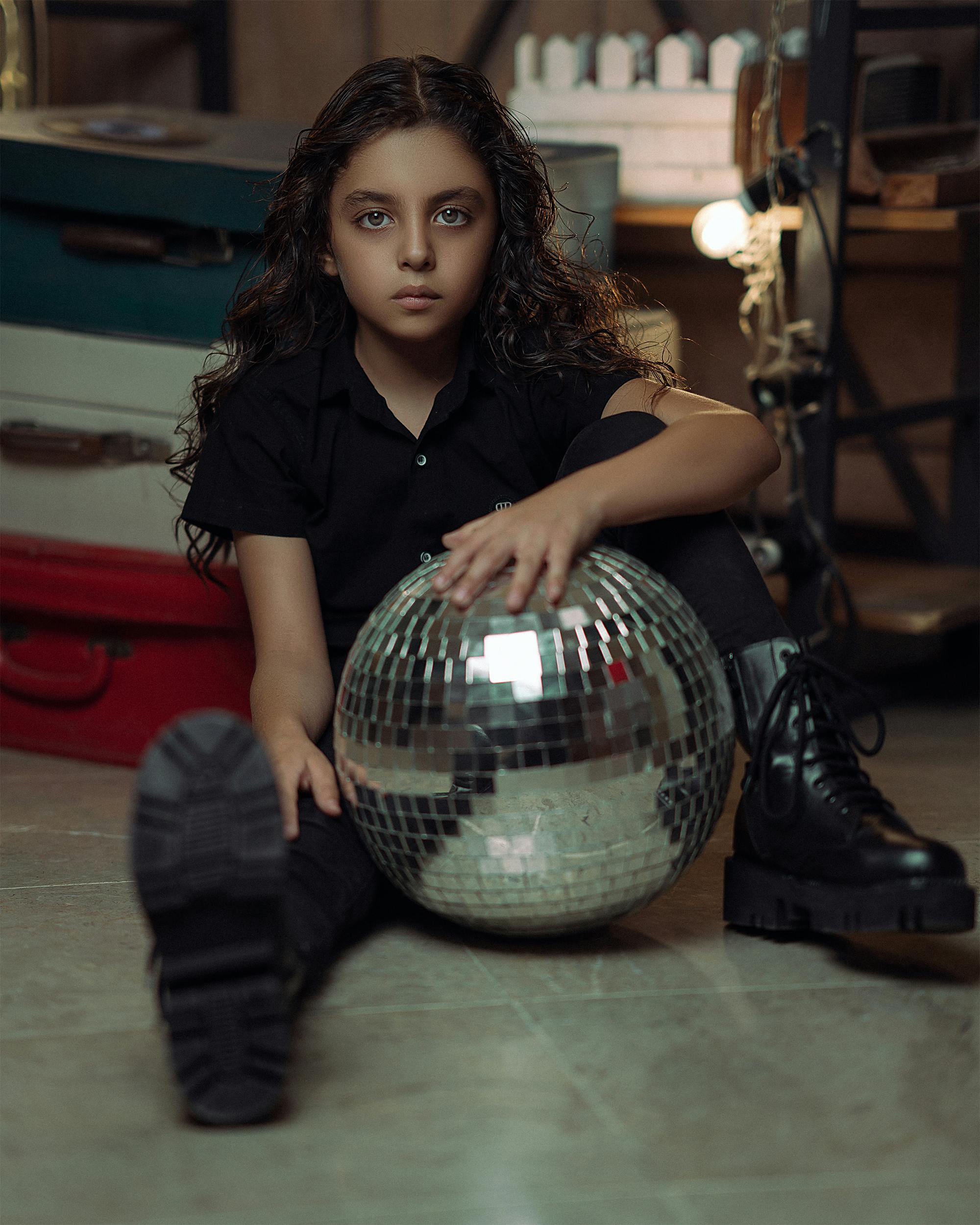 a girl sitting with a disco ball