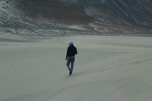 Back View of a Person Walking on Snow-Covered Ground