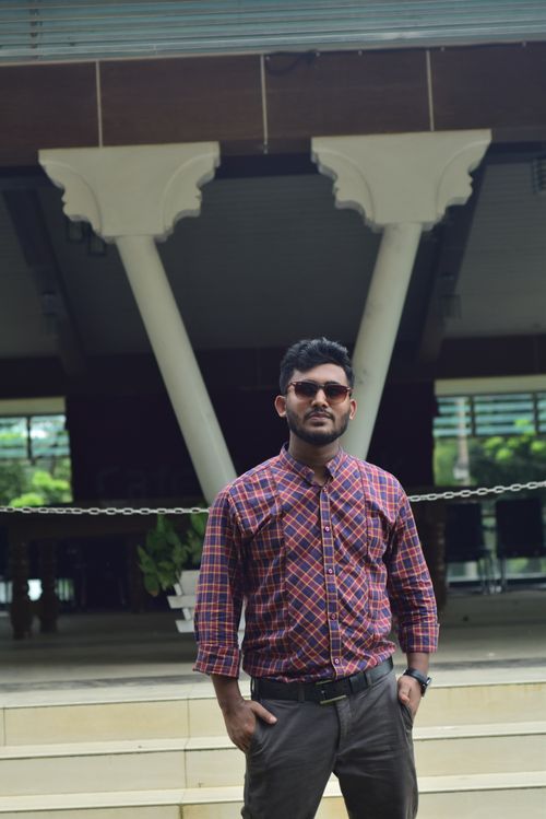 Free Confident man with sunglasses poses stylishly outdoors in a plaid shirt. Stock Photo
