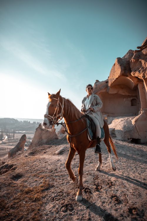 Free Woman on horseback in Göreme, Turkey with rock formations in the background. Stock Photo